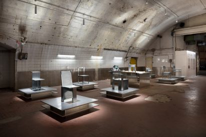 A series of steel chairs on podiums within a railway arch
