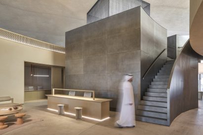 Man in traditional Emirati garb walking up to a steel staircase