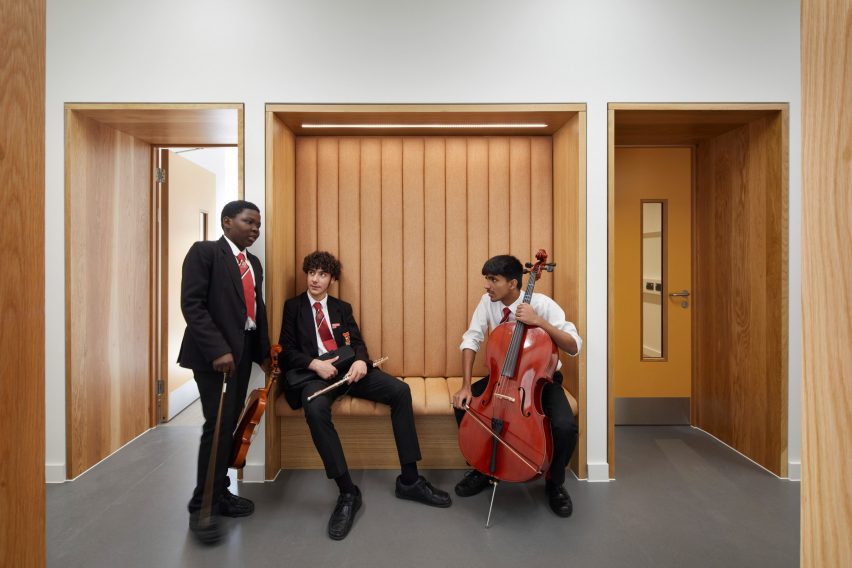 School children with musical instruments sitting on a wooden bench