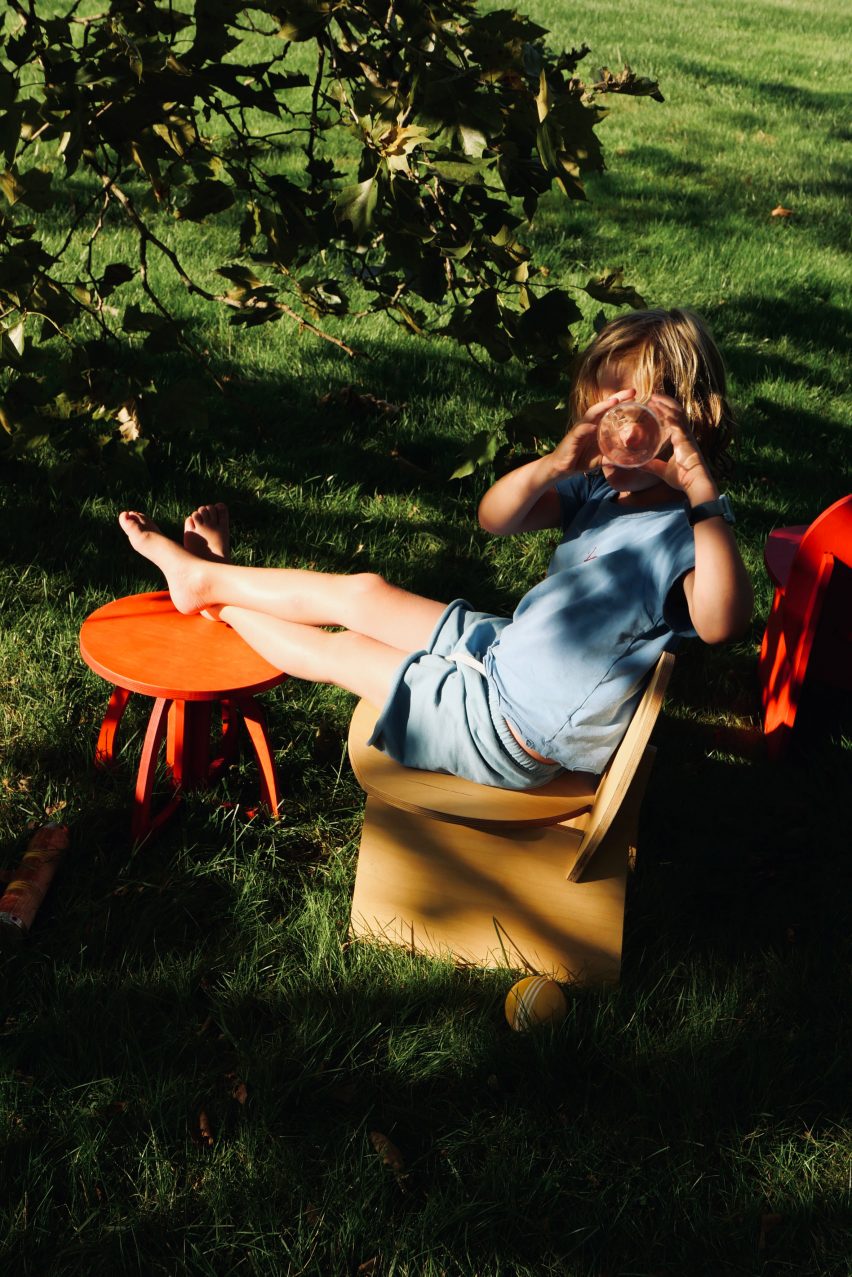A child sitting underneath a tree with their foot on a stool