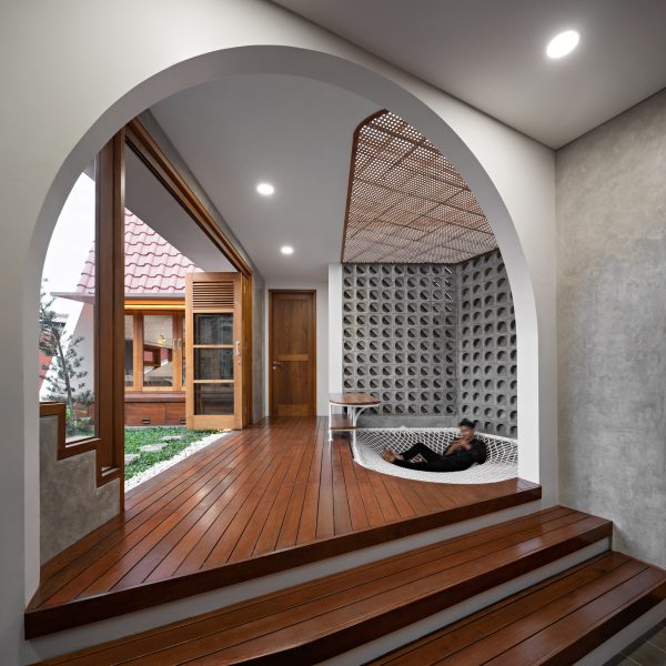 Interior space with wood flooring, concrete walls and open doors leading to a grassy terrace