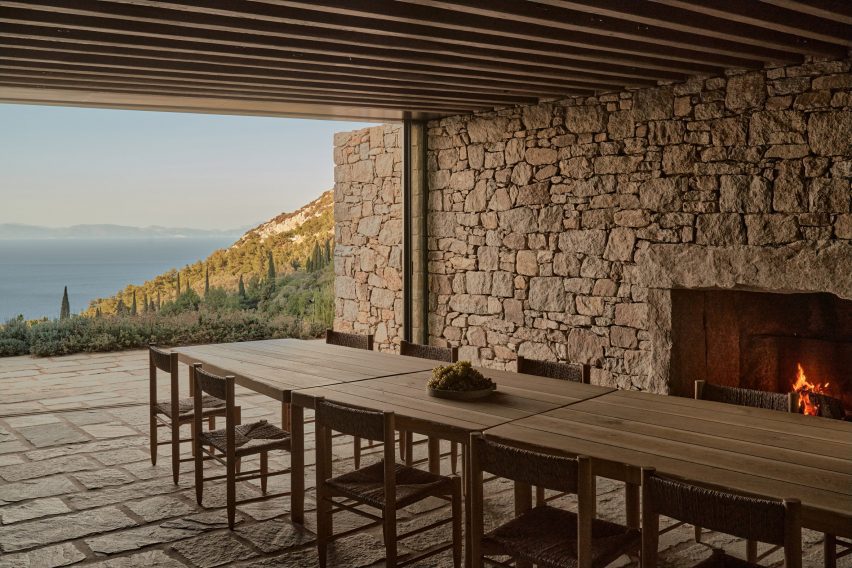 Wood dining table in a stone room with a terrace overlooking the sea