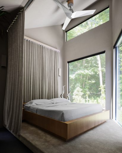 A bed on a raised carpeted platform, encircled by a linen curtain