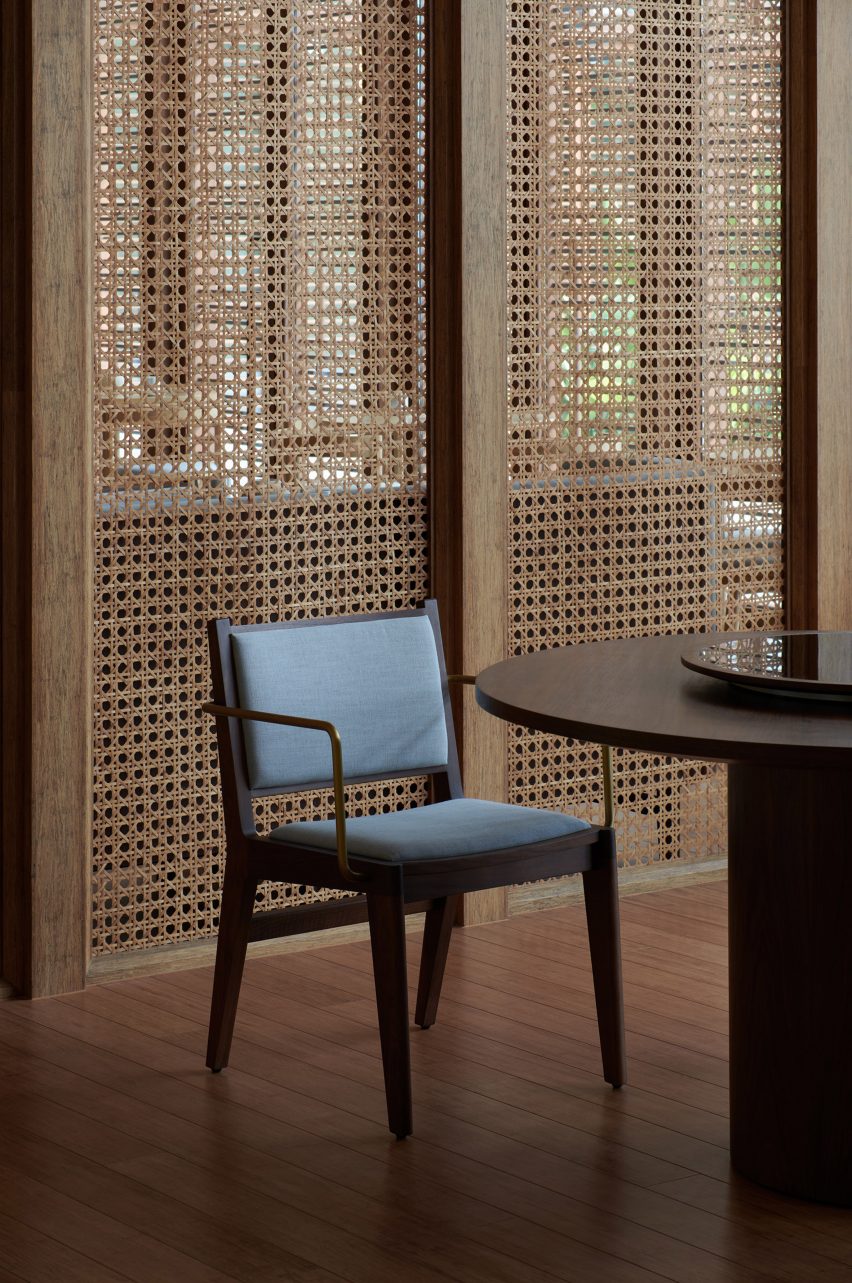 Upholstered wooden chair in front of a rattan screen