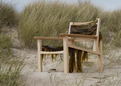 Wooden chair on sand dune draped in seaweed