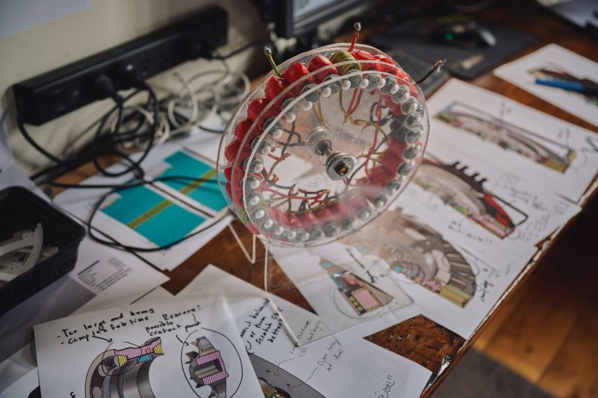 Photo of part from the REVR axial flux motor displayed on a work desk covered with design sketches