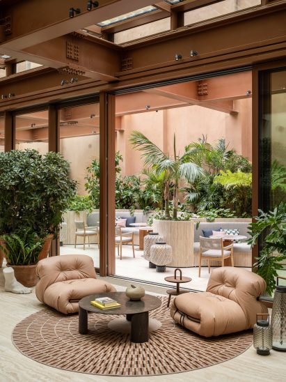 Lounge seats on a circular rug, in front of an opened glass partition in Six Senses Rome hotel by Patricia Urquiola