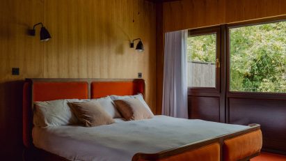 Bedroom in Zero House with wood-panelled walls and an orange carpet