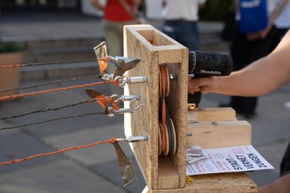 Close-up of a drill being used to wind up tarp into cords