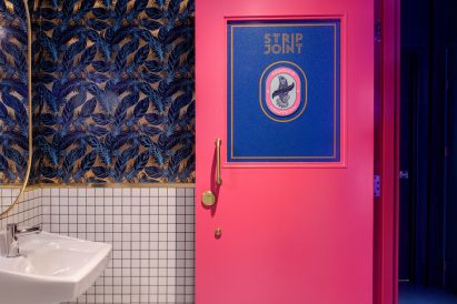 Bathroom with feathery wallpaper and a bright pink door