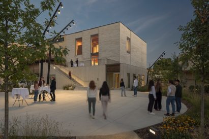 People walking into a cube build clad in beige