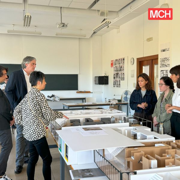 Photograph of students and lecturers discussing work that is on show.