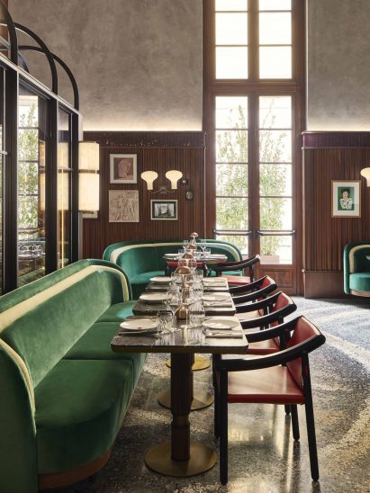 Seating area with bench and chairs inside restaurant by Humbert & Poyet