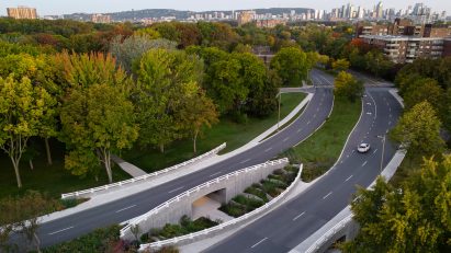 Curving bridge in forested environment with Montreal in background
