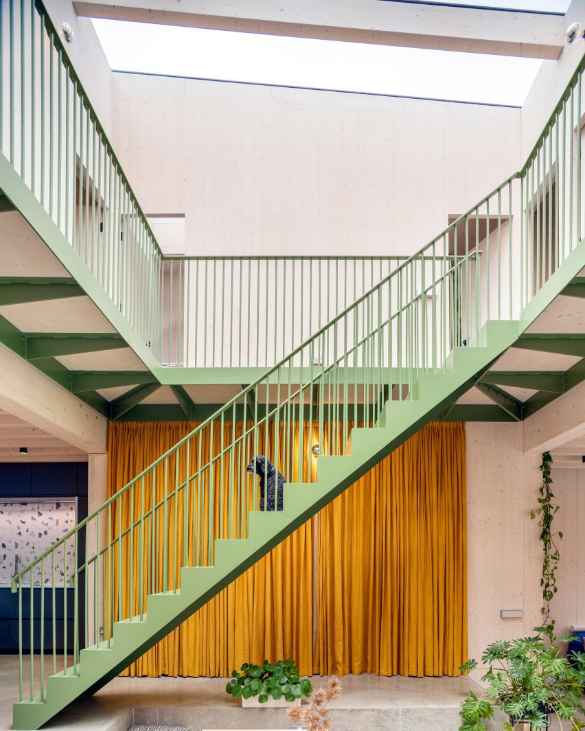 Green-painted metal staircase in a plywood-panelled atrium