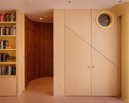 porthole in dark stair provides a glimpse of the room beyond