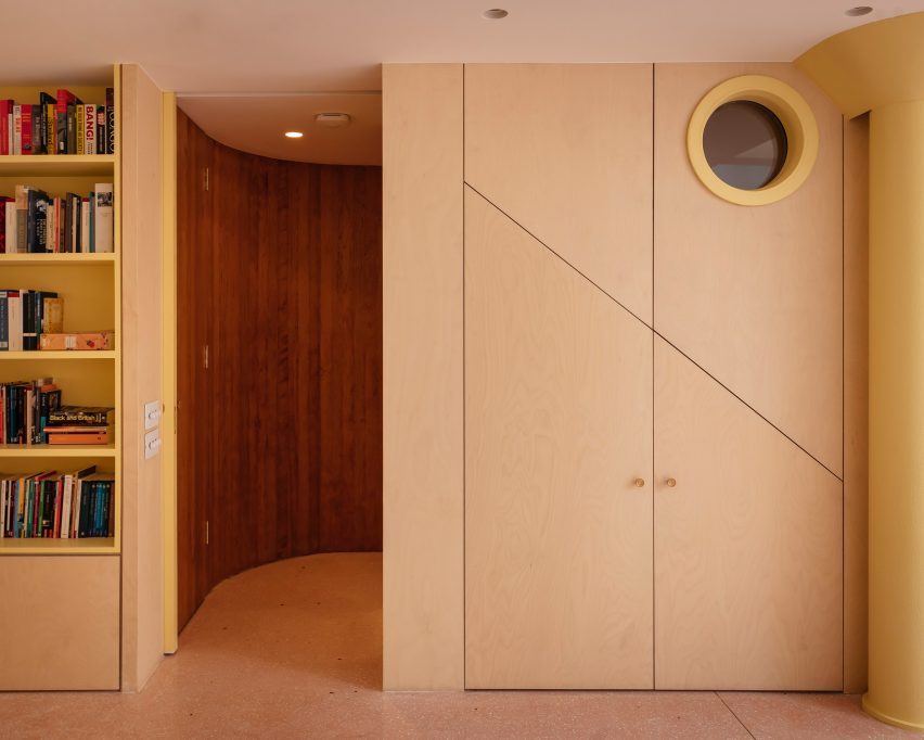porthole in dark stair provides a glimpse of the room beyond