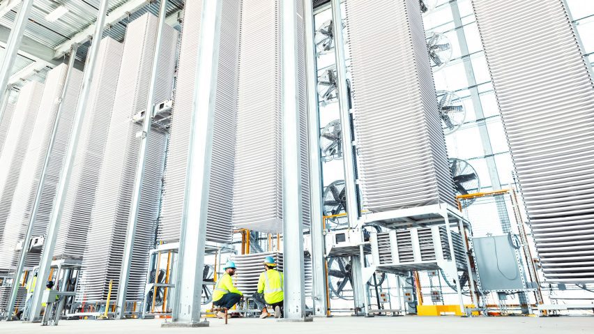 Two workers underneath the towers of a tall kiln