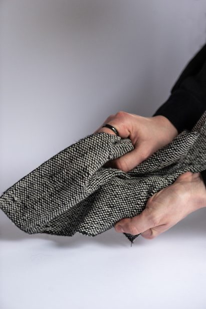 Photo of a pair of hands scrunching up a thick piece of black and white textured fabric