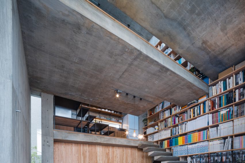 Floating concrete stairs on a bookshelf wall in a concrete home