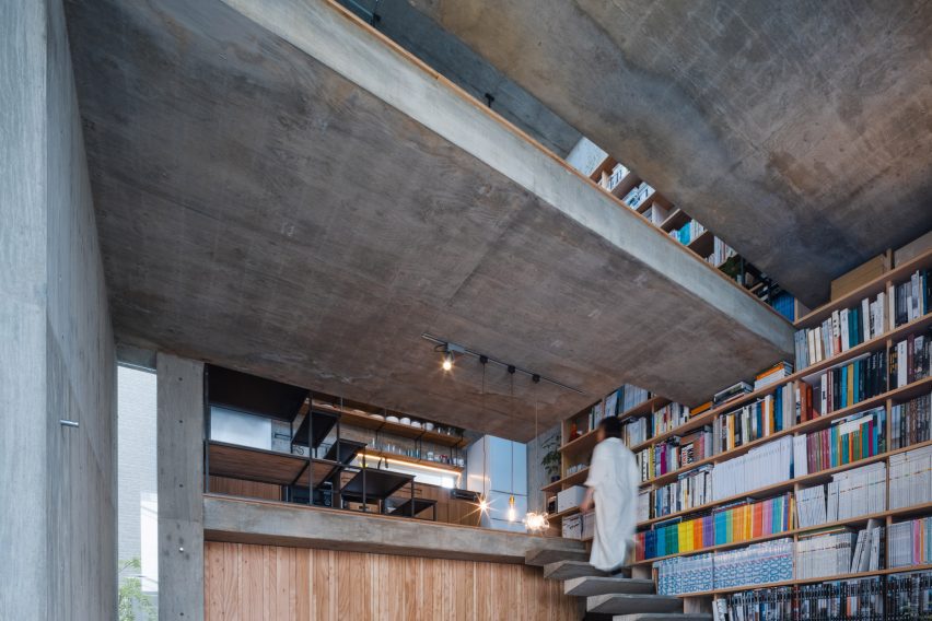 Floating concrete stairs on a bookshelf wall in a concrete home