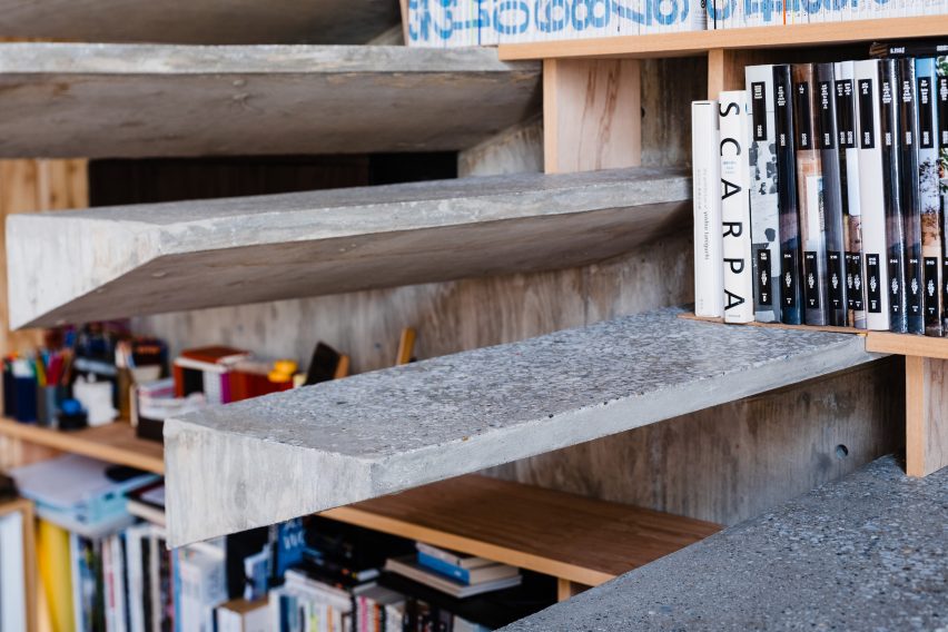 Floating concrete stairs on a bookshelf wall