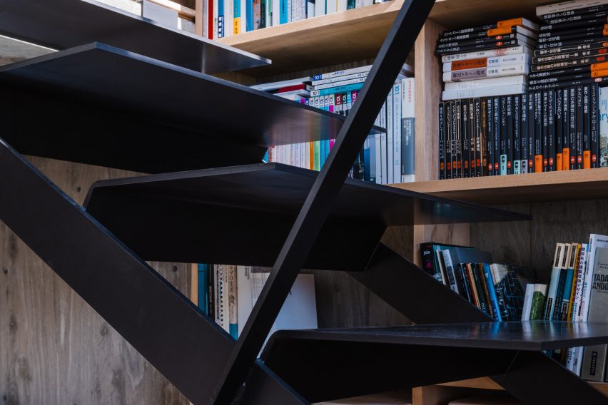 Black metal staircase next to bookshelves