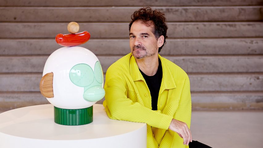 Jamie Hayon sitting next to a monkey head sculpture