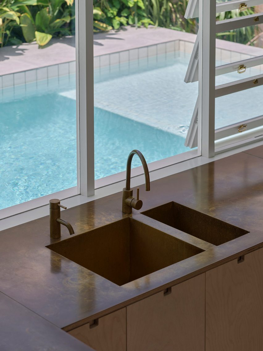 Kitchen sink by a window overlooking an outdoor swimming pool