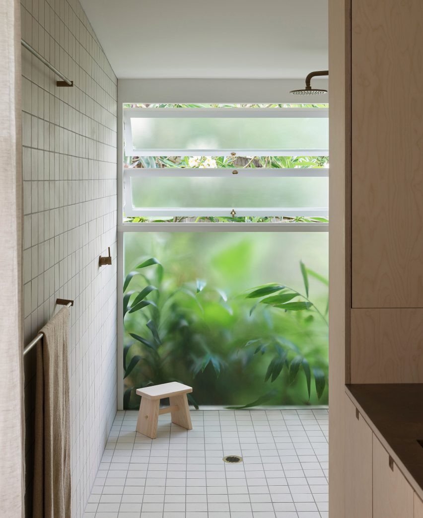 White-tiled bathroom with frosted windows next to planting