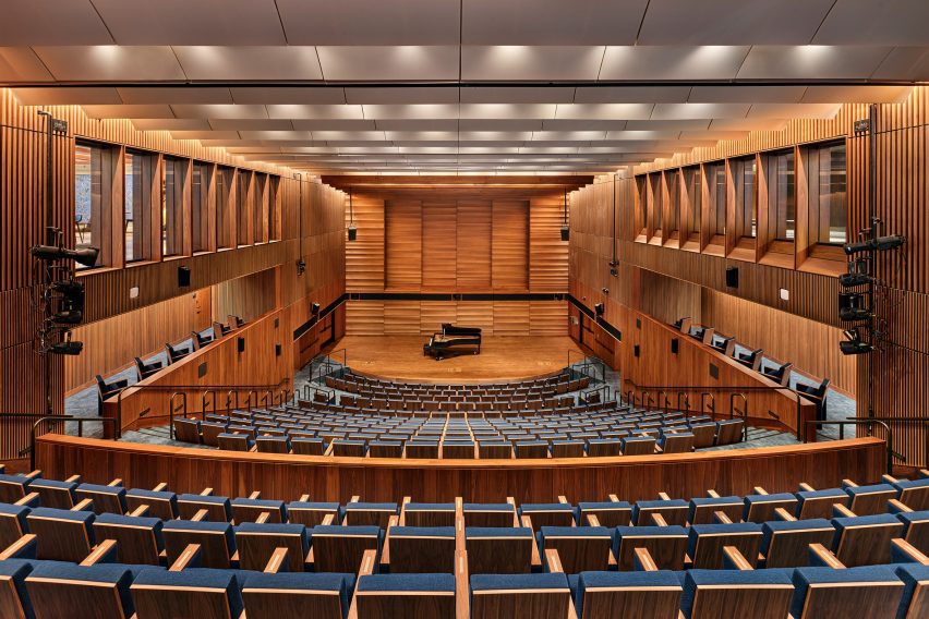A theatre with blue seating and wooden paneling