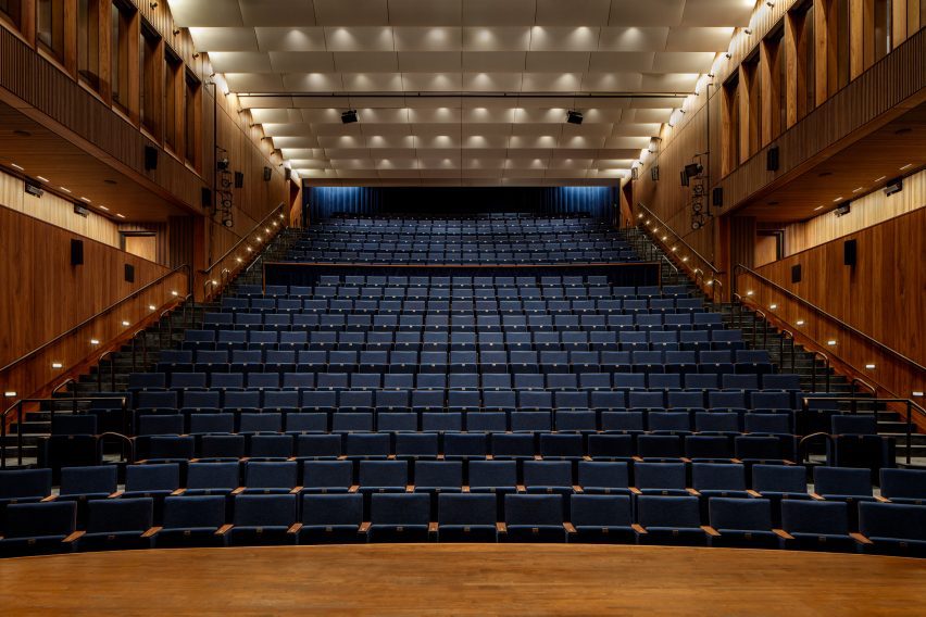 A theatre with blue seating and wooden paneling