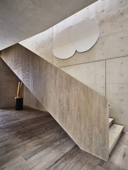 Staircase with a solid wood bannister against a concrete wall