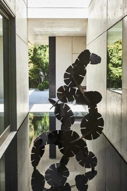 Abstract sculpture placed on a pool of water between concrete walls