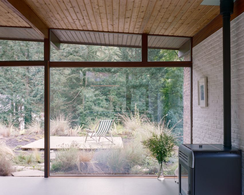 Glazed facade in a white-brick interior overlooking a wild garden