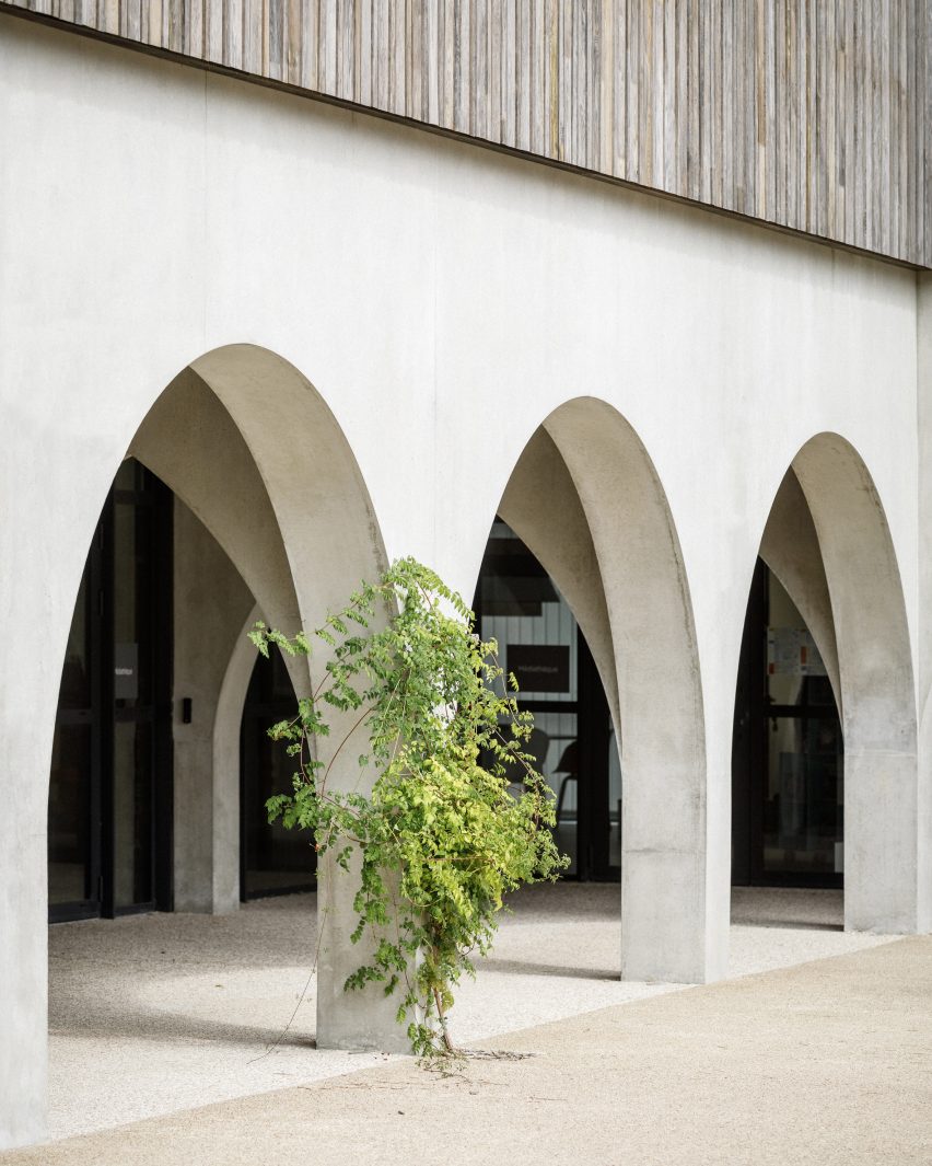 Arches in a concrete building with timber cladding on the upper level