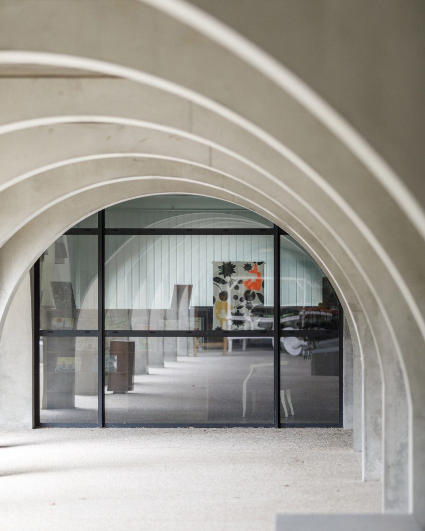 Wide concrete archways in front of a glass building