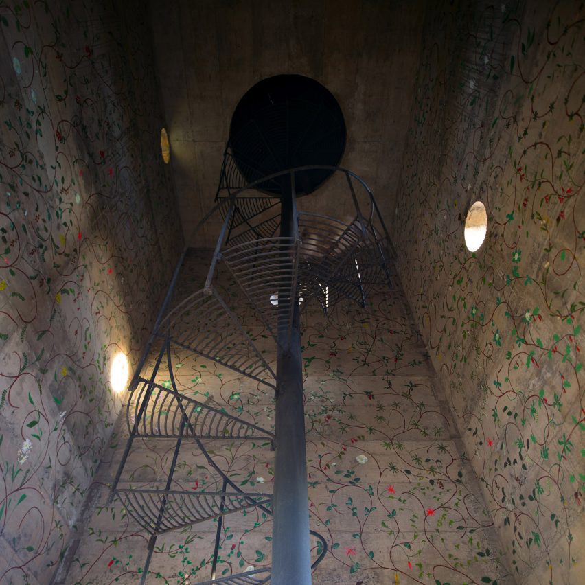 Spiral staircase surrounded by concrete walls with circular window opening
