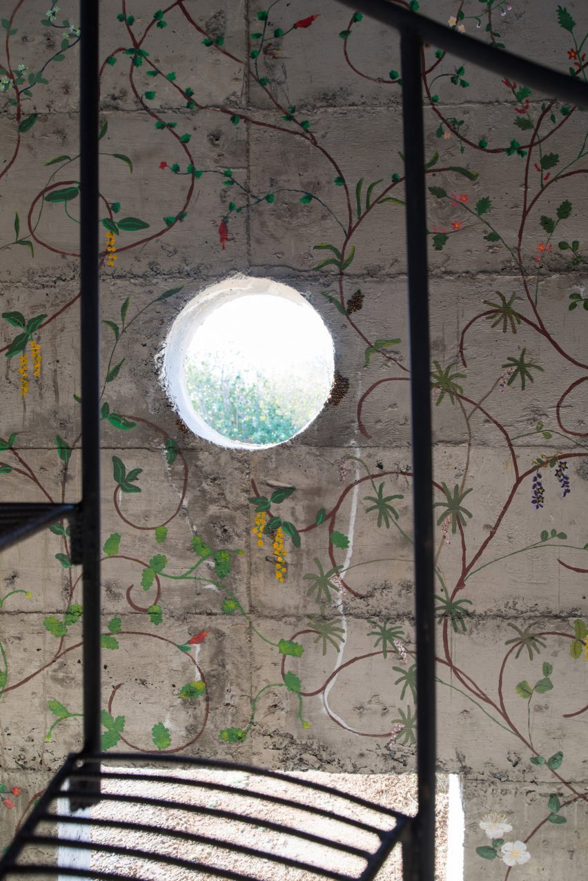 Circular window opening and painted flowers on concrete wall