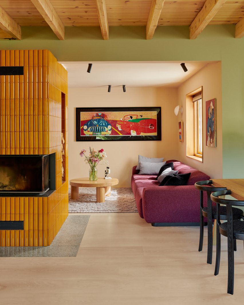 Fireplace with yellow tiles and lounge with plum-coloured sofa