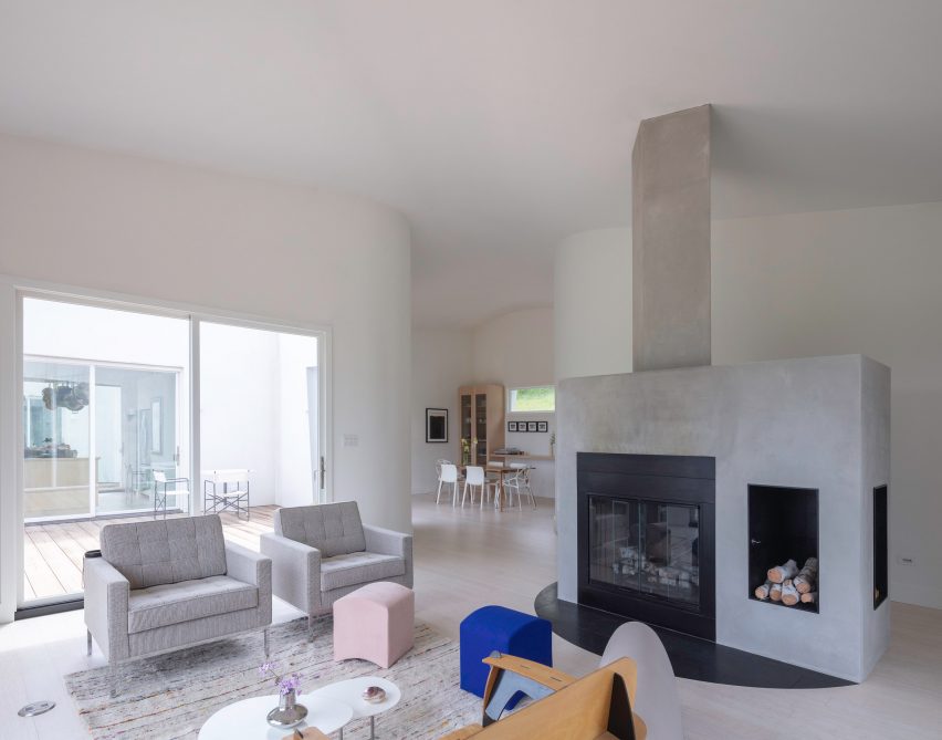 A large concrete fireplace in a white house with curved walls