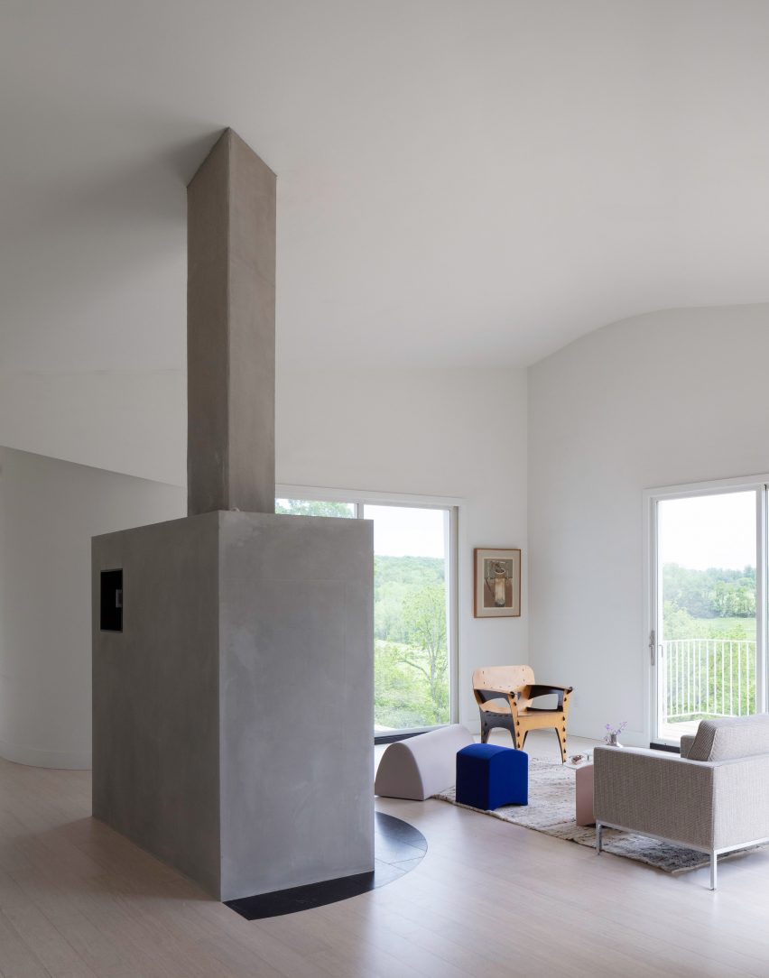A large concrete fireplace in a white house with curved walls