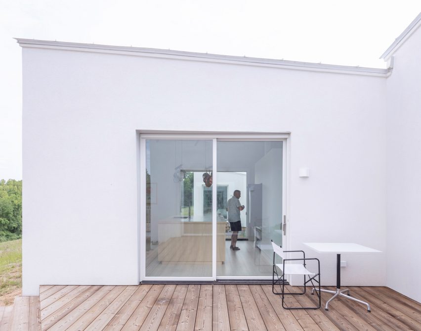 A wooden deck with sliding glass doors looking into kitchen
