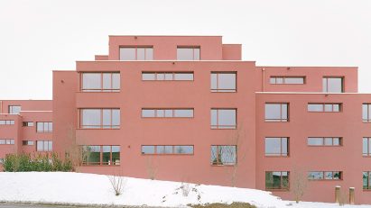 Ductus coats blocky apartment complex with red plaster in Switzerland