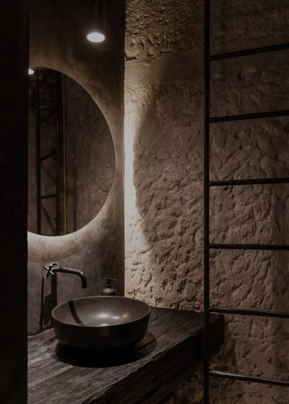 Dark bathroom with back-lit circular mirror
