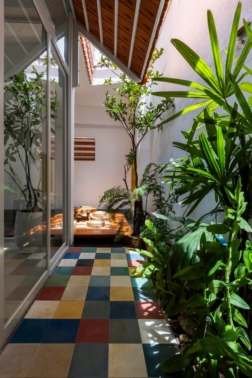 Interior with planting and multi-coloured square floor tiles at Tile House by The Bloom Architects