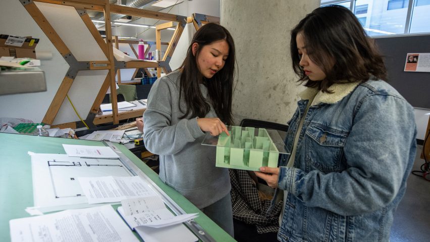 two interior architecture students are discussing their design based on an architectural model