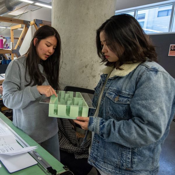 two interior architecture students are discussing their design based on an architectural model