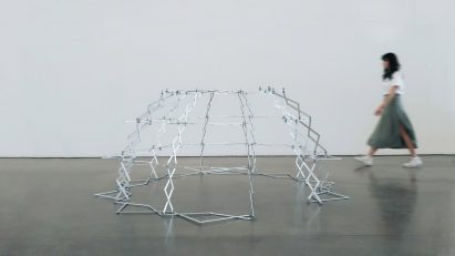Figure walking past structure made from bending metal components