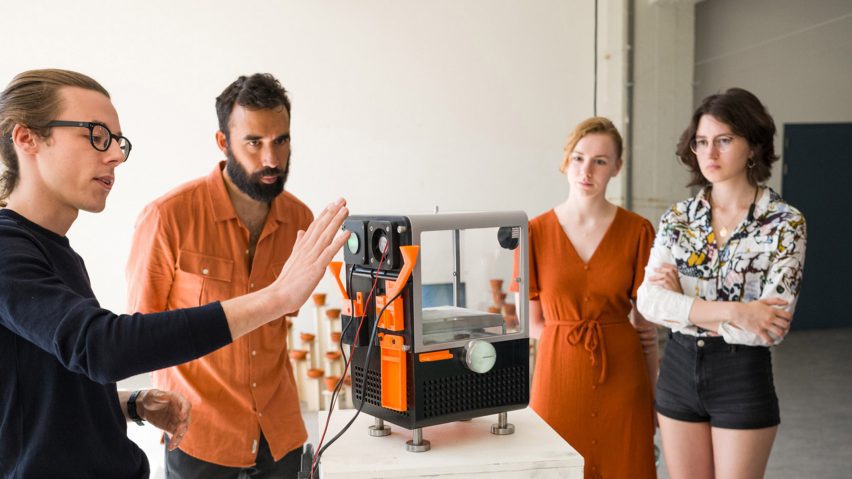 people looking at a cricket farming machine